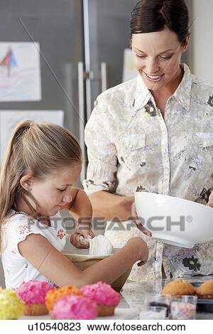 Stock Image - Mother and Daughter Making Cupcakes in kitchen. Fotosearch