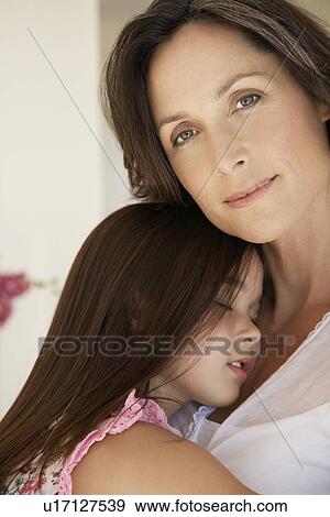 Stock Photo - Mother cuddling sleeping daughter head and shoulders. Fotosearch