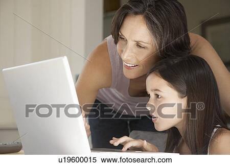 Mother helping daughter use laptop sitting at home View Large Photo Image Stock Photography - Mother helping daughter use laptop sitting at home. Fotosearch