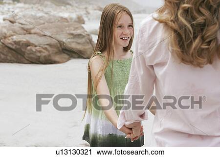 Stock Image - Mother playing with daughter (10-12) on beach. Fotosearch