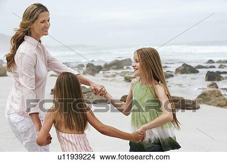 Picture - Mother playing with two daughters (7-9 10-12) on beach. Fotosearch