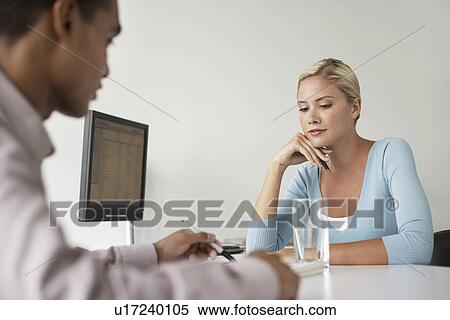 Stock Photography - Office worker and client sitting at desk side view. Fotosearch