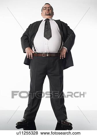 Stock Photo - Overweight businessman standing with thumbs in belt. Fotosearch