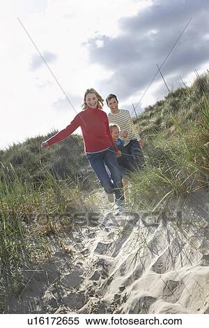 Parents and daughter (5-6) running through sand dunes View Large Photo Image Stock Photography - Parents and daughter (5-6) running through sand dunes. Fotosearch