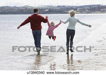 Parents lifting daughter (5-6) at ocean View Large Photo Image Stock Image - Parents lifting daughter (5-6) at ocean. Fotosearch