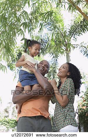 Stock Image - Parents with daughter (5-6 years) in tropical forest low angle view portrait. Fotosearch