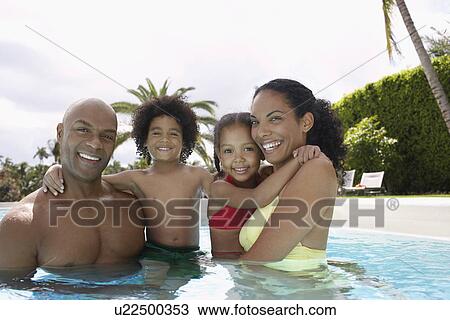 Stock Image - Parents with son and daughter (5-6 years) in pool portrait. Fotosearch