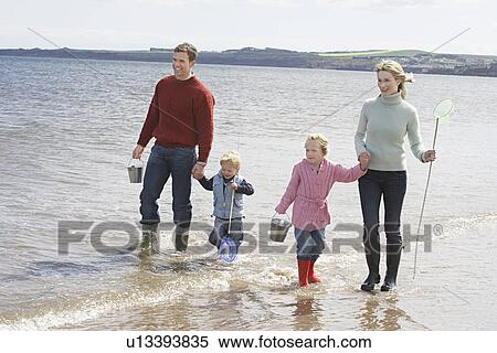 Parents with two children (3-6) walking in ocean View Large Photo Image Stock Photography - Parents with two children (3-6) walking in ocean. Fotosearch