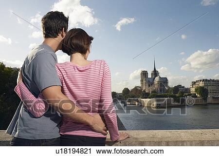 Stock Image - Paris France Couple embracing in front of Notre Dame Cathedral back view. Fotosearch