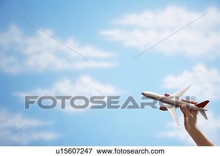 Stock Photo - Person holding model airplane against sky. Fotosearch