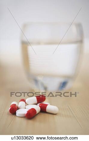 Pile of pills and glass of water on table close-up View Large Photo Image Stock Image - Pile of pills and glass of water on table close-up. Fotosearch