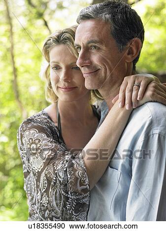 Stock Image - Portrait of couple embracing and smiling outdoors. Fotosearch