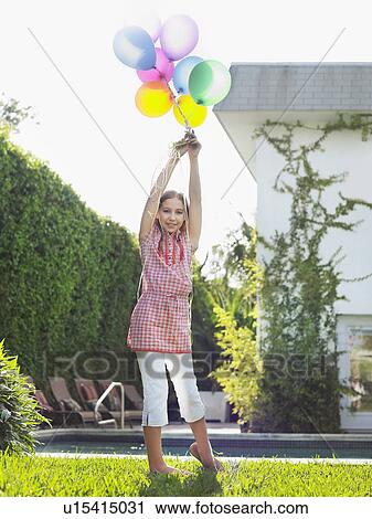 Portrait of girl (10-12) holding bunch of balloons over head View Large Photo Image Stock Image - Portrait of girl (10-12) holding bunch of balloons over head. Fotosearch