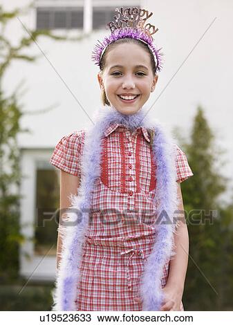 Stock Image - Portrait of girl (10-12) in tiara and feather boa. Fotosearch