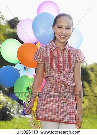 Portrait of girl (10-12) with bunch of balloons smiling View Large Photo Image Stock Image - Portrait of girl (10-12) with bunch of balloons smiling. Fotosearch