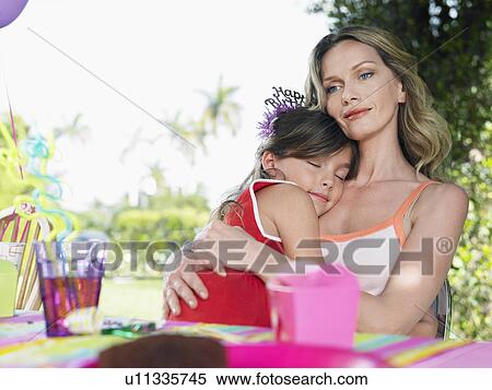 Stock Photography - Portrait of mother and daughter (7-9) at birthday table girl sleeping close-up. Fotosearch