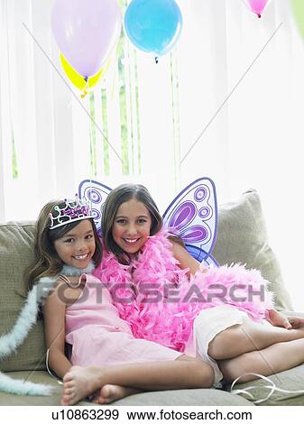 Portrait of two girls (7-9 10-12) sitting on sofa in party costumes View Large Photo Image Stock Photo - Portrait of two girls (7-9 10-12) sitting on sofa in party costumes. Fotosearch
