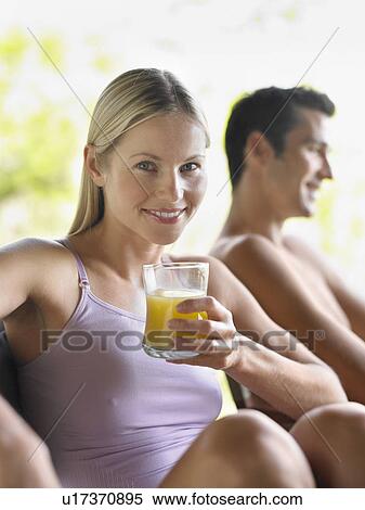 Stock Photography - Portrait of woman holding glass of juice man in background focus on foreground. Fotosearch