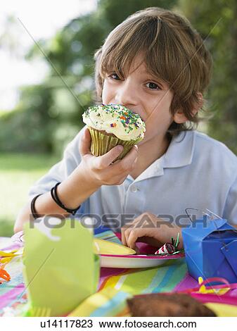 Portrait of young boy (10-12) eating cupcake at birthday party View Large Photo Image Stock Image - Portrait of young boy (10-12) eating cupcake at birthday party. Fotosearch
