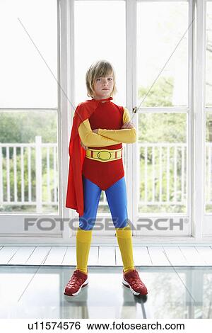 Stock Photograph - Portrait of young boy (7-9) in superhero costume indoors. Fotosearch