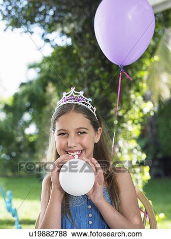 Portrait of young girl (10-12) wearing tiara blowing up balloons View Large Photo Image Stock Photo - Portrait of young girl (10-12) wearing tiara blowing up balloons. Fotosearch
