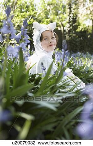 Stock Image - Portrait of young girl (5-6) sitting in flowers in horse costume. Fotosearch