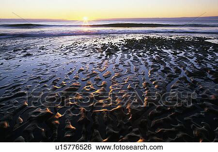 Stock Photograph - Ripples in beach at sunrise. Fotosearch