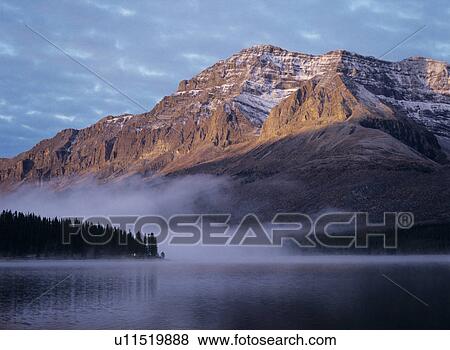 Rocky mountain fog over lake sunset View Large Photo Image Stock Photo - Rocky mountain fog over lake sunset. Fotosearch