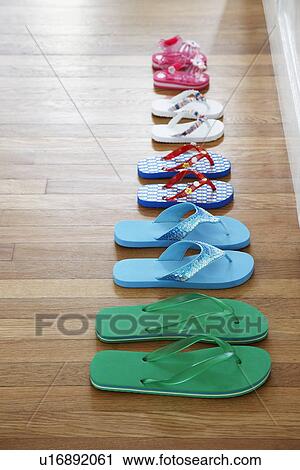 Stock Image - Row of flip-flops on floor elevated view. Fotosearch