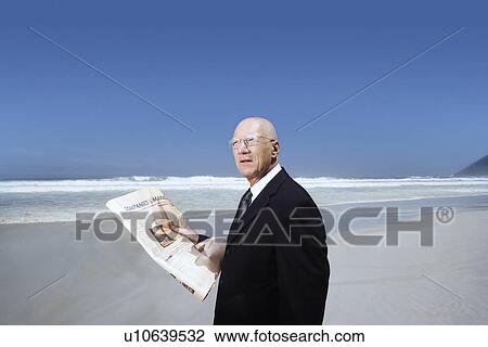 Senior business man holding newspaper standing on beach portrait View Large Photo Image Stock Image - Senior business man holding newspaper standing on beach portrait. Fotosearch
