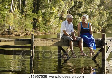 Senior Couple sitting on dock by lake. View Large Photo Image Stock Photograph - Senior Couple sitting on dock by lake.. Fotosearch