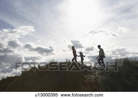 Silhouette of parents and daughter (5-6) walking on sand dunes View Large Photo Image Stock Photography - Silhouette of parents and daughter (5-6) walking on sand dunes. Fotosearch