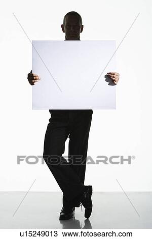 Silhouetted man standing holding large blank card View Large Photo Image Stock Image - Silhouetted man standing holding large blank card. Fotosearch