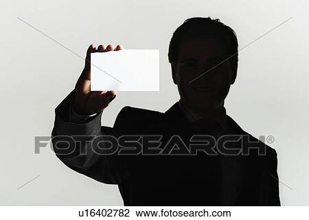 Silhouetted man standing holding large blank card View Large Photo Image Stock Image - Silhouetted man standing holding large blank card. Fotosearch