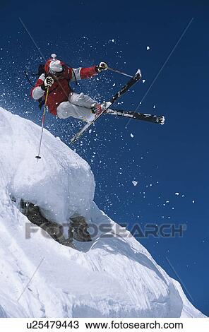 Stock Image - Skier in mid-air above snow on ski Slopes. Fotosearch