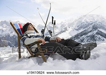 Picture - Skier resting on deckchair in mountains. Fotosearch