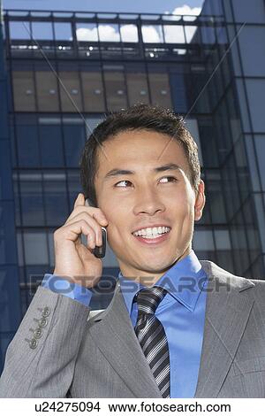 Smiling Businessman Using Cell Phone outside building View Large Photo Image Picture - Smiling Businessman Using Cell Phone outside building. Fotosearch