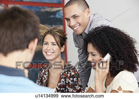 Stock Photo - Smiling Businesspeople listening to colleague in meeting Using Cell Phone in Meeting. Fotosearch