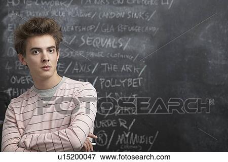 Stock Photo - Smiling young man in front of blackboard. Fotosearch
