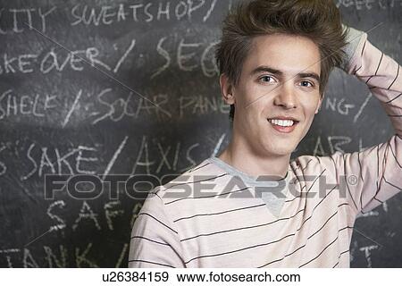 Smiling young man in front of blackboard View Large Photo Image Stock Photo - Smiling young man in front of blackboard. Fotosearch