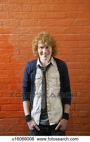 Smiling young man standing in front of brick wall View Large Photo Image Stock Photo - Smiling young man standing in front of brick wall. Fotosearch