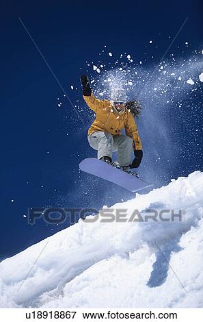 Stock Photo - Snowboarder mid-air above ski Slope snow powder trailing behind. Fotosearch