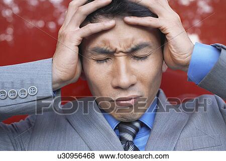 Stock Photo - Stressed Businessman holding head in hands eyes closed close-up. Fotosearch