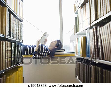 Student lying down on windowsill in library reading View Large Photo Image Stock Image - Student lying down on windowsill in library reading. Fotosearch