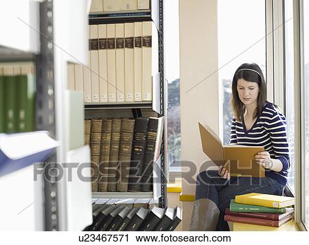 Student sitting on windowsill in library reading View Large Photo Image Stock Image - Student sitting on windowsill in library reading. Fotosearch