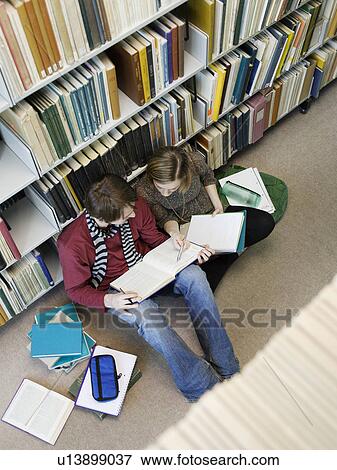 Stock Photo - Students sitting on floor doing homework in library. Fotosearch
