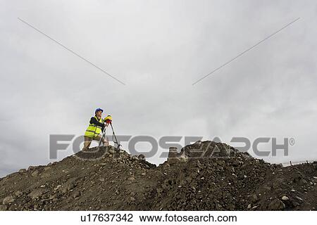 Stock Image - Surveyor using theodolite on site. Fotosearch