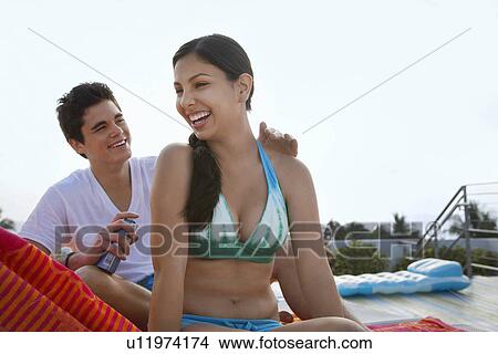 Teenage boy (16-17) applying sunscreen lotion to girl's back View Large Photo Image Picture - Teenage boy (16-17) applying sunscreen lotion to girl's back. Fotosearch