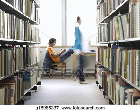 Stock Photo - Teenage boy doing homework in library. Fotosearch