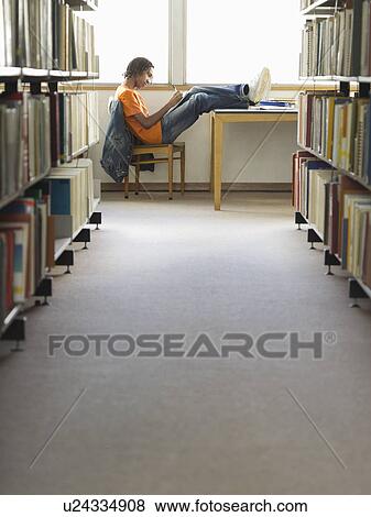 Stock Photo - Teenage boy doing homework in library. Fotosearch